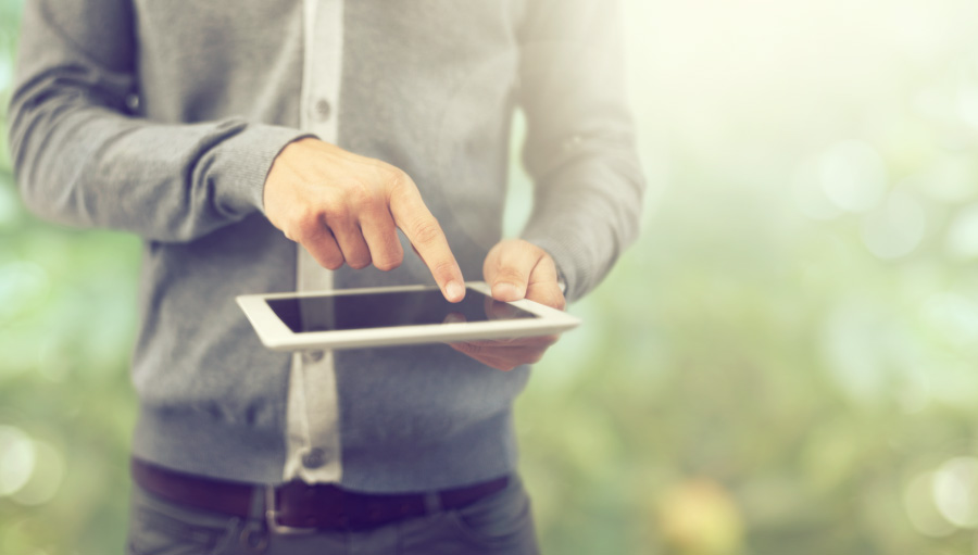 torso of man in gray sweater standing outside pointing at tablet looking up what gingivitis is