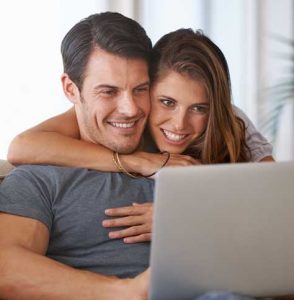 Couple hugging looking at laptop
