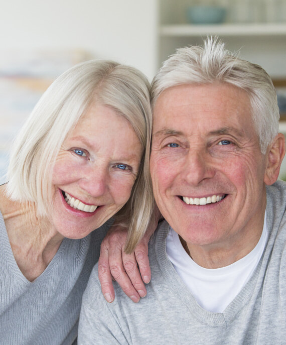 elderly couple with dental implants smiling