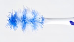 Overhead view of a blue and white toothbrush with worn bristles that appear spread out and smashed