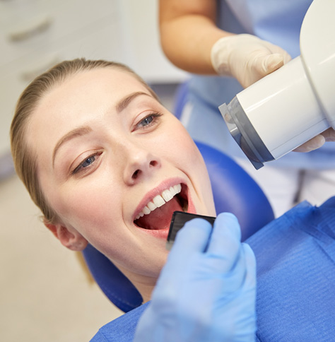 blonde woman lying in dental chair getting dental X-ray taken