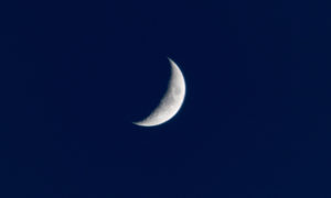 White crescent moon against a dark navy blue midnight sky