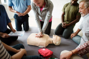 A group of people learn and practice CPR with an AED on a dummy torso