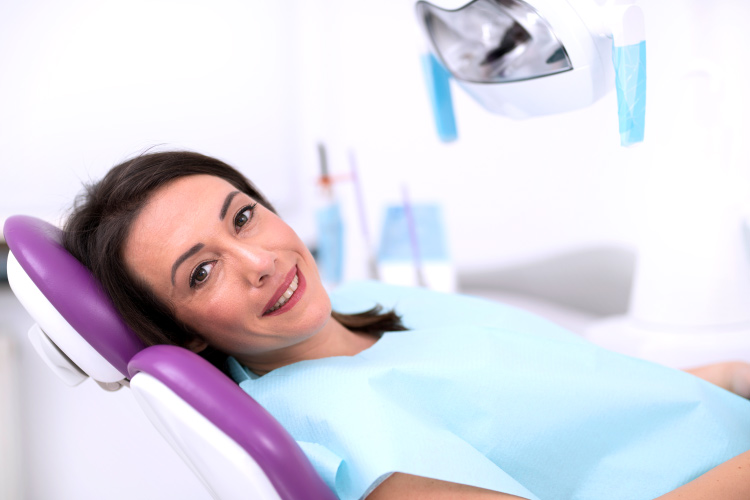 Smiling brunette woman in dental chair waiting for a dental implant procedure