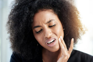 Attractive young black woman with a pained look on her face and her hand to her jaw indicating dental abscess pain
