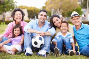 Multigenerational hispanic family sitting at the park with a soccer ball.
