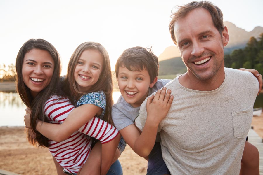 Young family with two kids standing in front of a lake.